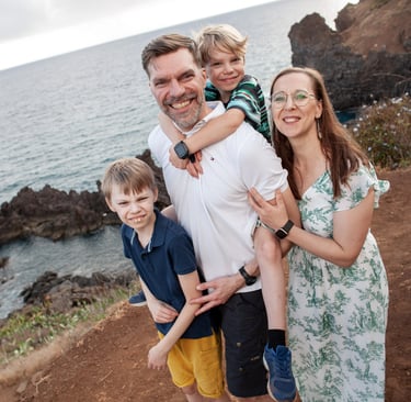 Smiling family poses together on Lido cliffs above Atlantic Ocean at Madeira, lifestyle travel and natural coastal scenery.