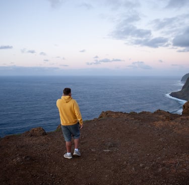 	Man in yellow jacket overlooking Atlantic Ocean at sunset Madeira