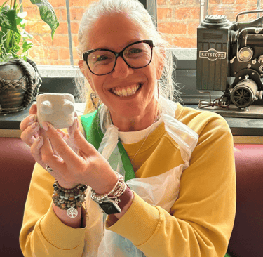 happy hen holding her clay boob pot