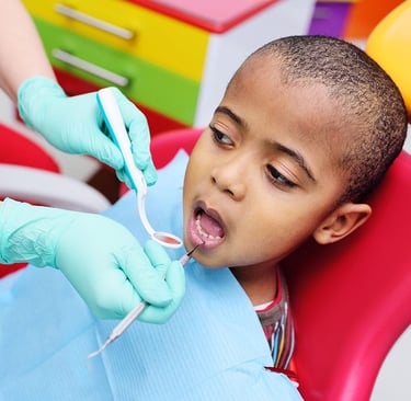 Young boy receiving emergency dental checkup from a dentist using a mouth mirror and probe.