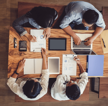 a group of people sitting at a table with laptops