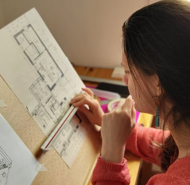 a woman is sitting at a desk with a drawing of a house
