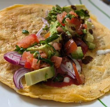 An Indian Kathi Roll with omelet layered on top of a Lacha Parantha and a filling of avocado, red onion and tomatoes 