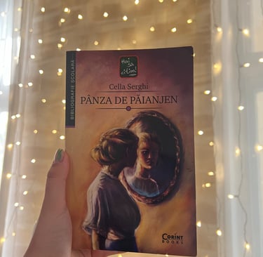 Mână ținând cartea 'Panza de paianjen' de Cella Serghi pe un fundal de luminițe de basm.