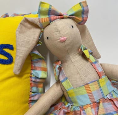 Handmade linen bunny doll wearing a colorful plaid dress and matching bow tie.