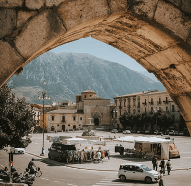 Veduta della piazza principale di Sulmona attraverso un arco in pietra