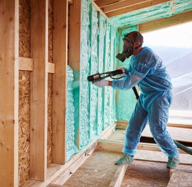 Worker spraying blue foam insulation