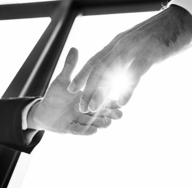 Dos manos a punto de estrecharse con un halo de luz en medio de ambas.
