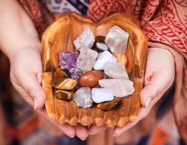 a person holding a bowl of tumbled stones