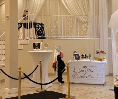 Wedding photo booth rental with blue and white paper flower backdrop, props table, and white kiosk.