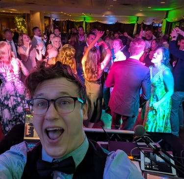wedding DJ poses for a selfie in front of a packed dance floor