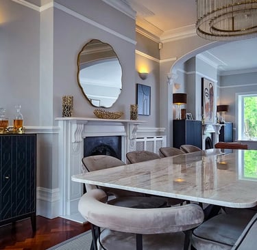 Sleek dining area with a marble table, velvet chairs, and modern chandeliers in an open-plan space