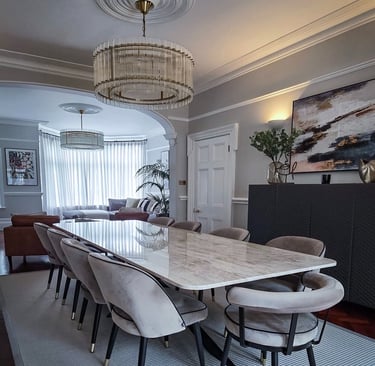 Sleek dining area with a marble table, velvet chairs, and modern chandeliers in an open-plan space
