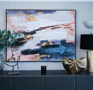 A piece of colourful modern art placed above a black counter, with gold accents in the decoration