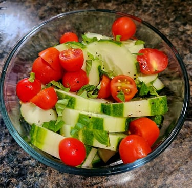 a bowl of cucumbers and tomatoes on a counter