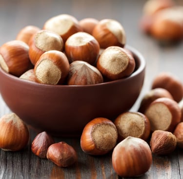 a bowl of nuts and hazells on a wooden table