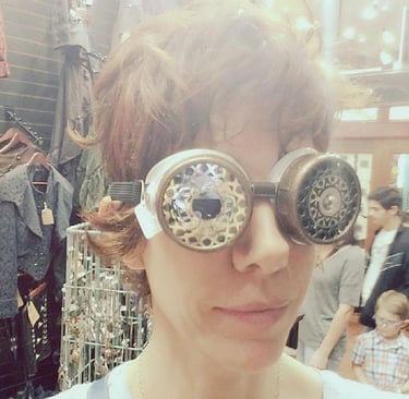 close up head shot of a woman in short hair wearing steampunk goggles