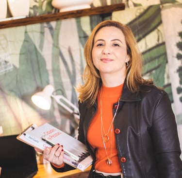 Professional woman in a leather jacket holding books in a stylish office workspace.