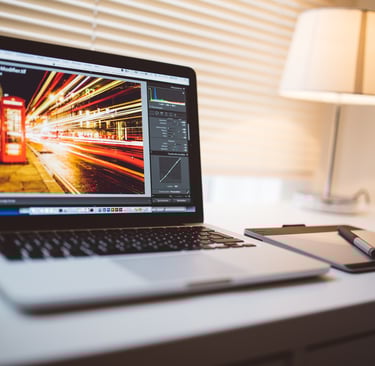open laptop sitting on a white desk with the laptop screen showing sped up traffic and light