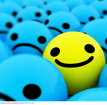 Imágenes que representan un rostro sonriente entre varios serios indicando que eres optimista