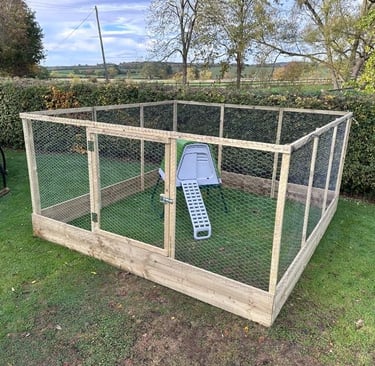 Large wooden chicken run with wire mesh and a small coop on a green lawn.