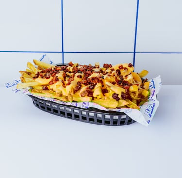 Patatas fritas de Flipa cortadas a mano diariamente, con salsa de quesos y bacon bits