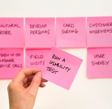 A hand holding a pink sticky note