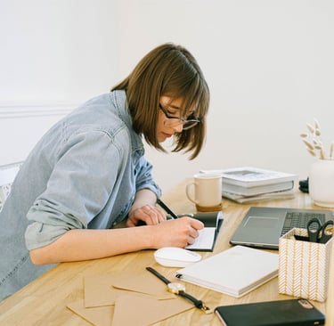A woman writing on a notepad while sitting in her work station