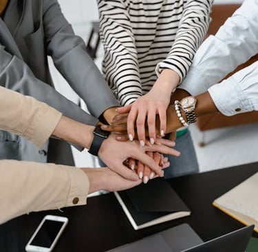 A team celebrating success by putting their hands together