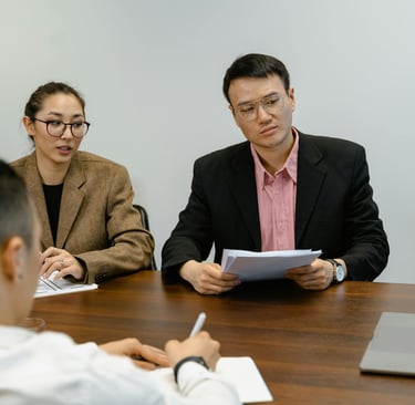 Three people in an office watching a person delivering a consultation service virtually 