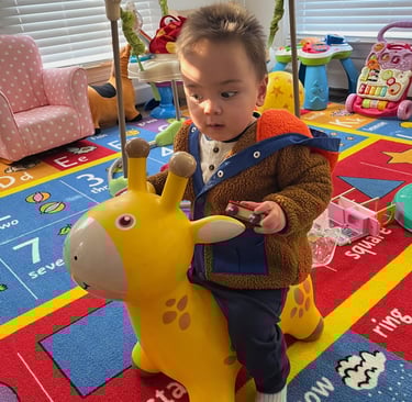 Photo of child playing on a yellow bouncy toy.
