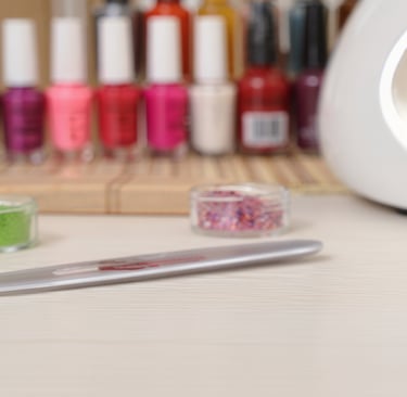 lime, brillantini lampade e smalti appoggiati su un tavolo di legno bianco