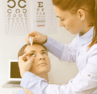 an optometrist administering eyedrop in a woman's eye