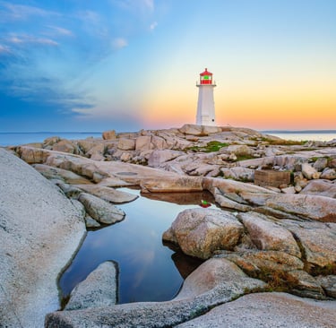 lighthouse with rocks in foreground and sun behind