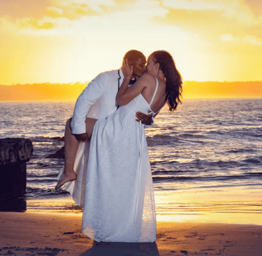 black bride and groom kissing on beach with golden sunset