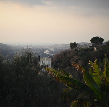 Panoramic view of a hillside village in Nice, France, overlooking the Var river valley at sunset.