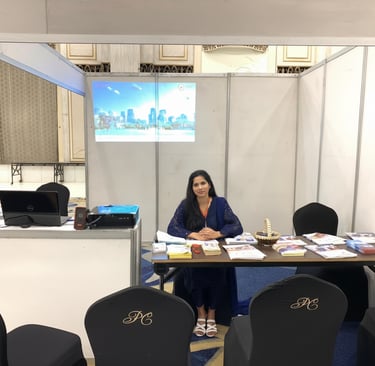"Professional immigration consultant seated at an exhibition booth with a city skyline projection.