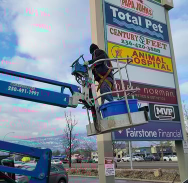 "Technician performing maintenance on a large outdoor sign, ensuring optimal function.