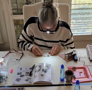 Assembling the DIY book nook kit at a table with miniature pieces and instructions.