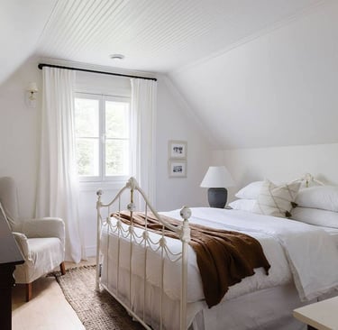 Une chambre avec un lit, une lampe et un cadre artistique
