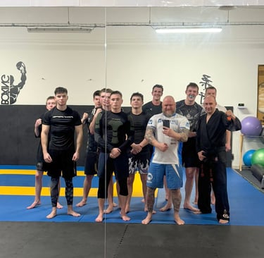 A group of MMA and martial arts athletes posing for a mirror selfie during training in a combat sports gym.