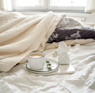 a cup of coffee and a tray on a bed