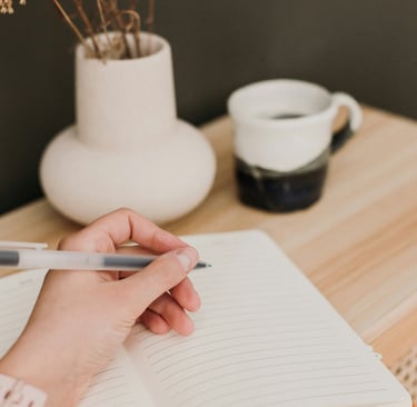 a person holding a pen and writing on a notebook