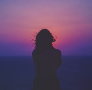a woman standing in front of a sunset