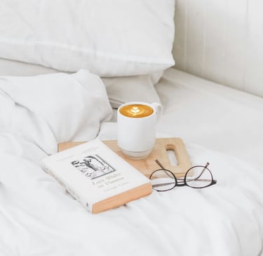 a cup of coffee and a book on a bed