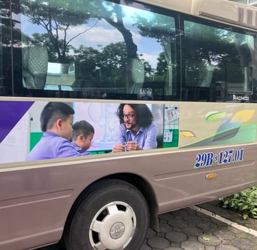 A bus with a advertisement of a school. The advertisement has a male teacher teaching students.
