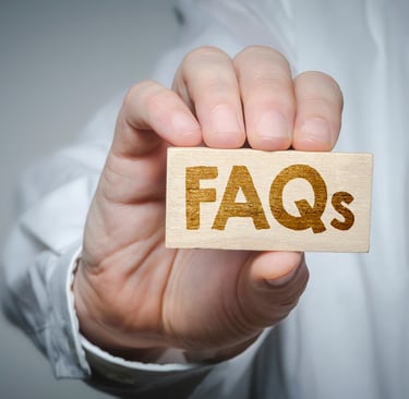 a person holding a wooden block with the word faqs on it