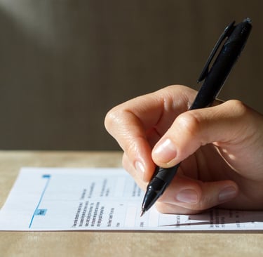 a person's hand holding a pen and writing on a piece of paper