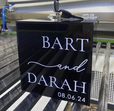 Elegant black acrylic box displaying 'Bart and Darah, 08.06.24' in white cursive font, a chic choice