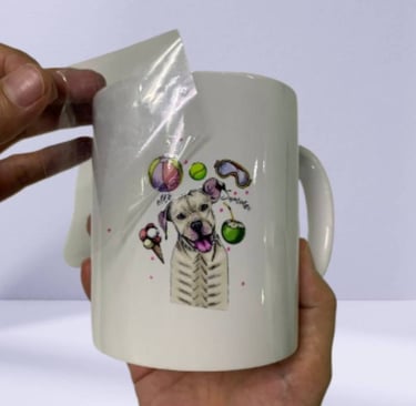 UV DTF sticker being applied to a white ceramic mug with a dog design.